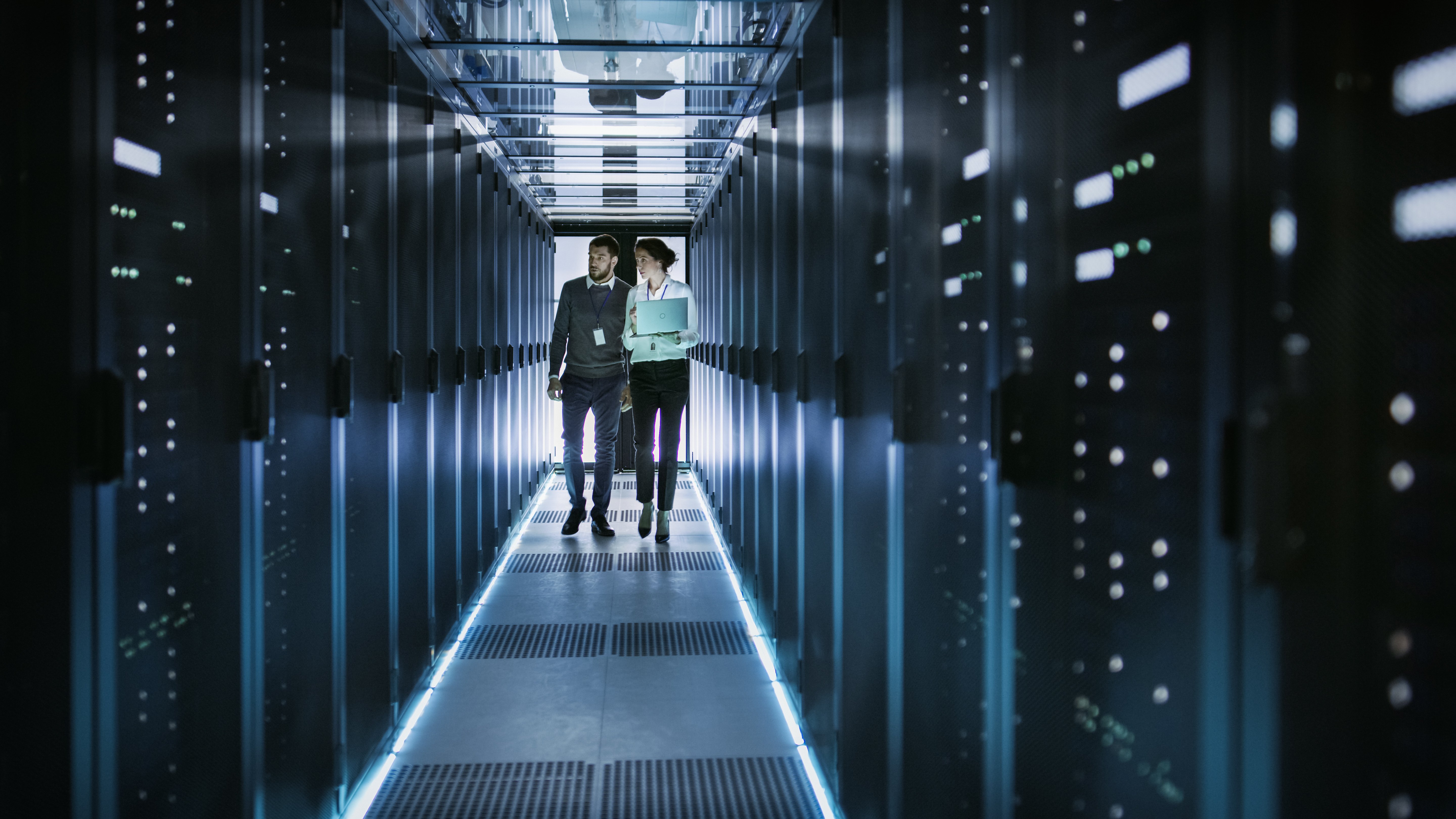 IT businessman and businesswoman walking through servers in a data center